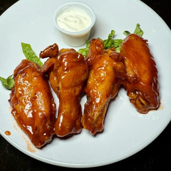 Four American-style chicken wings coated in a glossy orange sauce, served with a side of ranch dressing.